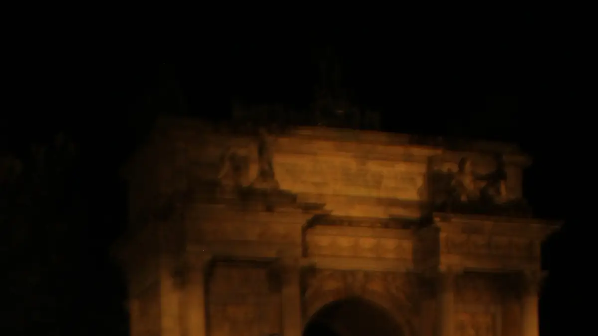 L’Arco della Pace illuminato, di notte, con la gente in piazza