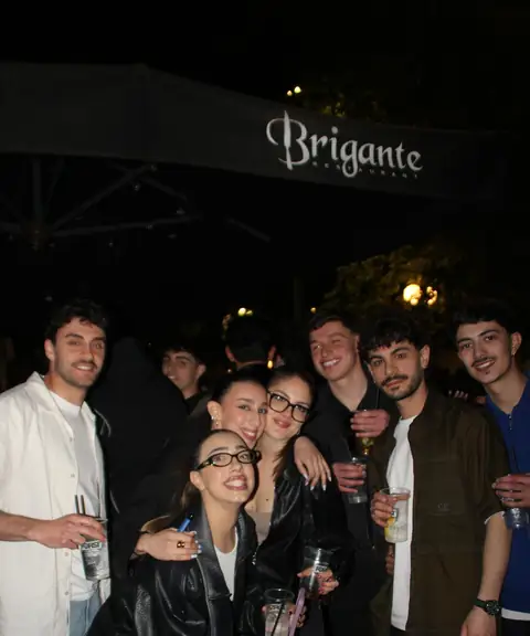 Un gruppo di amici sotto l’ombrellone con l’insegna Brigante