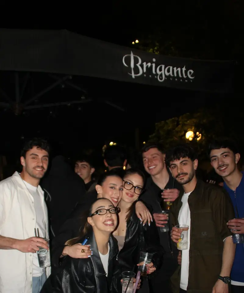Un gruppo di amici sotto l’ombrellone con l’insegna Brigante